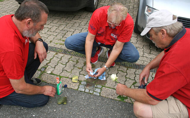 Uwe Speit, Thomas Gans und Rainer Jakobi reinigen den Stolperstein für Karl Pape in der Hauptstraße