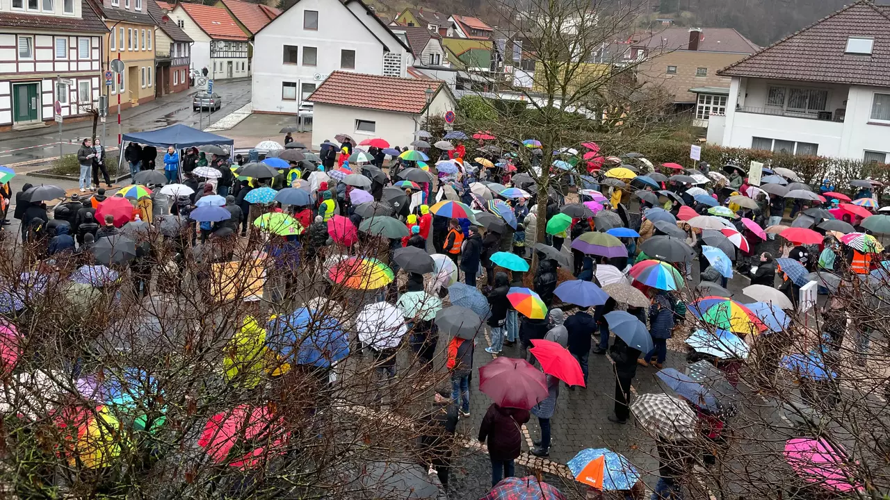 Menschenmenge mit bunten Regenschirmen demonstriert auf dem Krichparkplatz