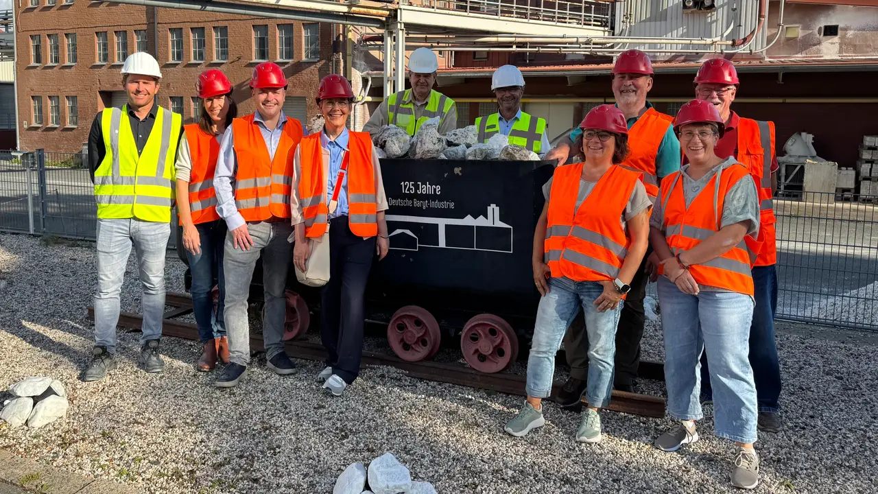 Gruppe von SPD-Kommunalpolitikern mit Sicherheitswesten und Helm vor einer historischen Lore mit Schwerspat-Gestein auf dem Werksgelände der Deutschen Baryt-Industrie in Bad Lauterberg