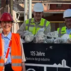 Gruppe von SPD-Kommunalpolitikern mit Sicherheitswesten und Helm vor einer historischen Lore mit Schwerspat-Gestein auf dem Werksgelände der Deutschen Baryt-Industrie in Bad Lauterberg