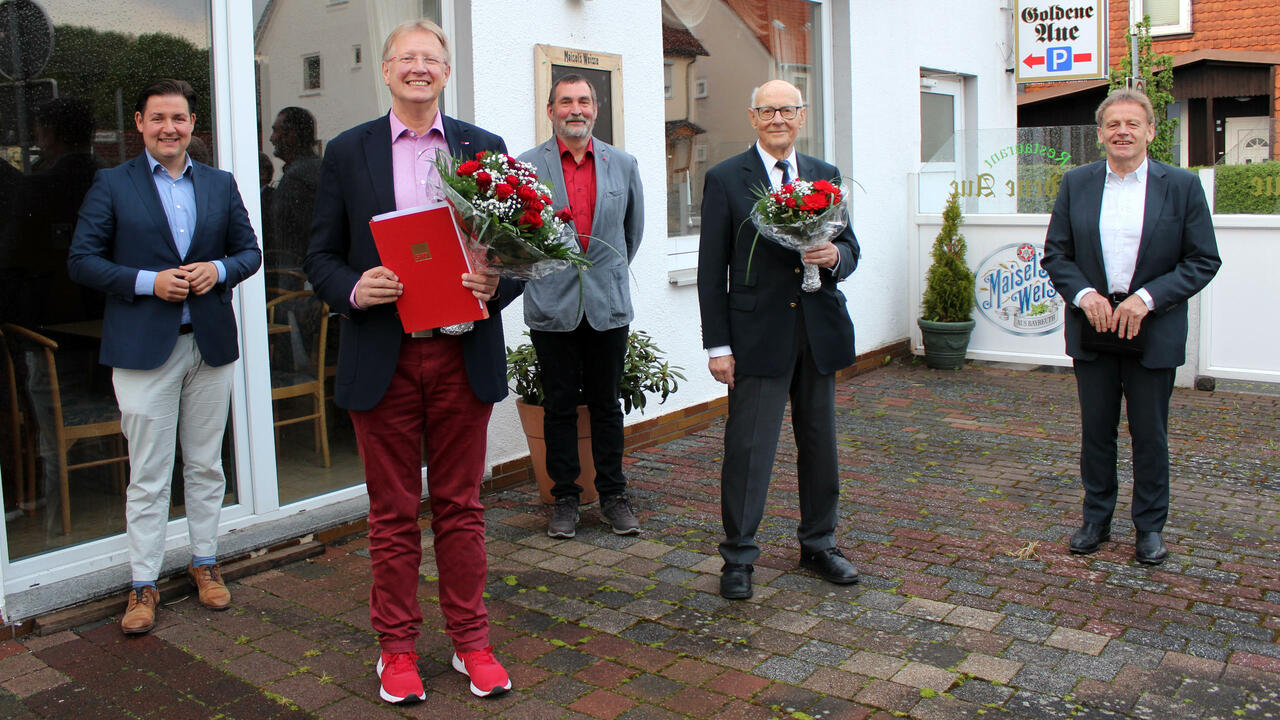 Gruppe von Personen vor der Golenden Aue mit Urkunden und Blumensträußen in der Hand.